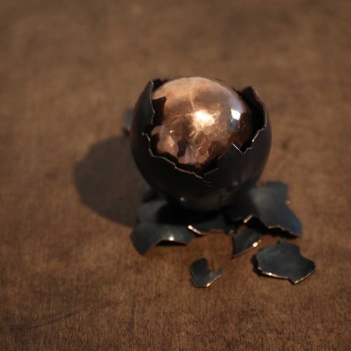 Cracked egg with copper center and dark metal exterior