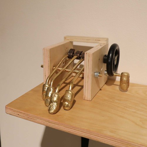 Mechanical artwork in wood and brass that mimics moving fingers.