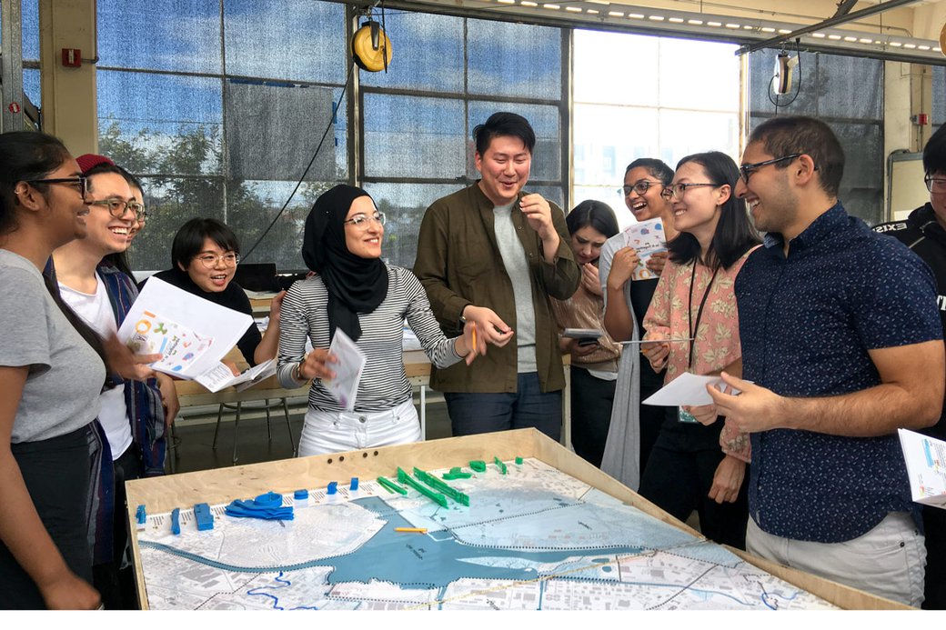 Students laugh while standing around a large map.