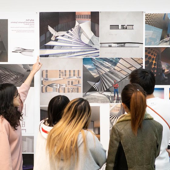 Students viewing critique materials on a wall.