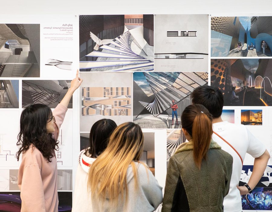 Students viewing critique materials on a wall.