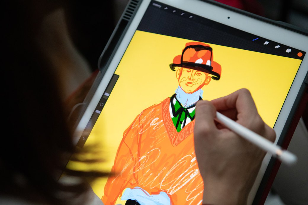 Fashion student sketching outfits on an iPad tablet.