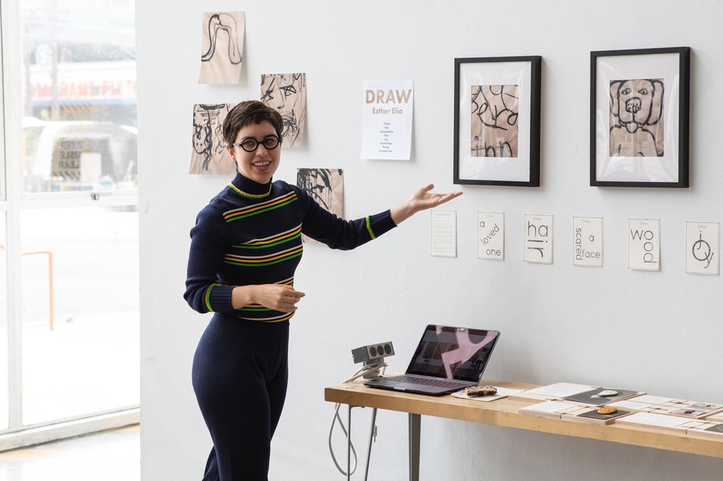 A student presents a framed artwork during a presentation.
