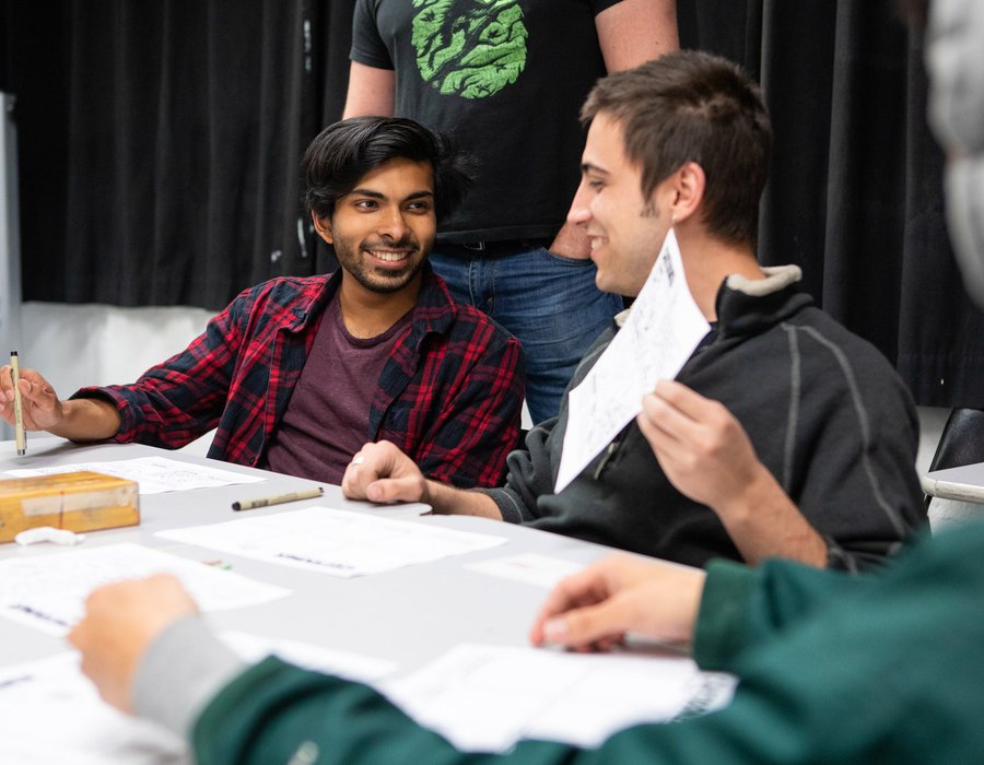 Two writing students laugh about the comics they've created in class.