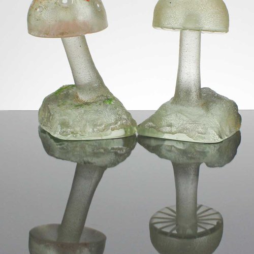 Two mushrooms with red tops made by Tanner Relyea from sand cast glass.