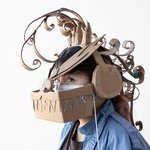 A student wears a headdress resembling a dragon made out of cardboard.