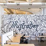 The word illustration is drawn into a mural of branches and leaves adorning a large classroom wall