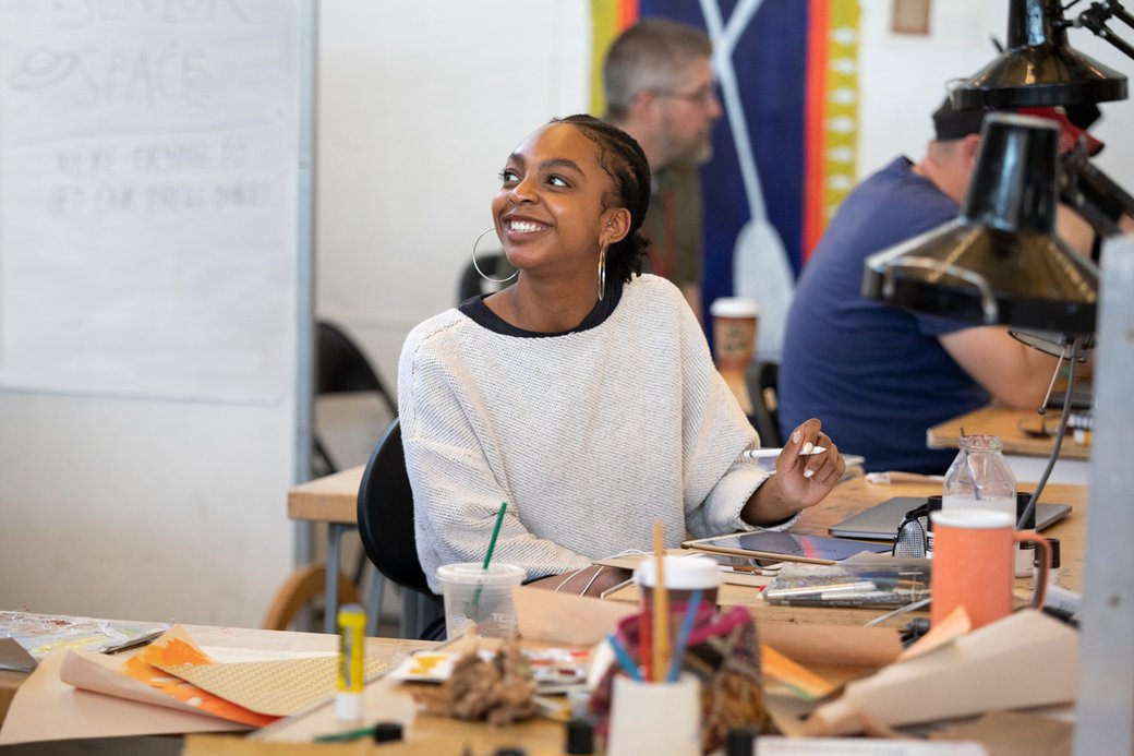 Illustration student smiling while drafting in her studio