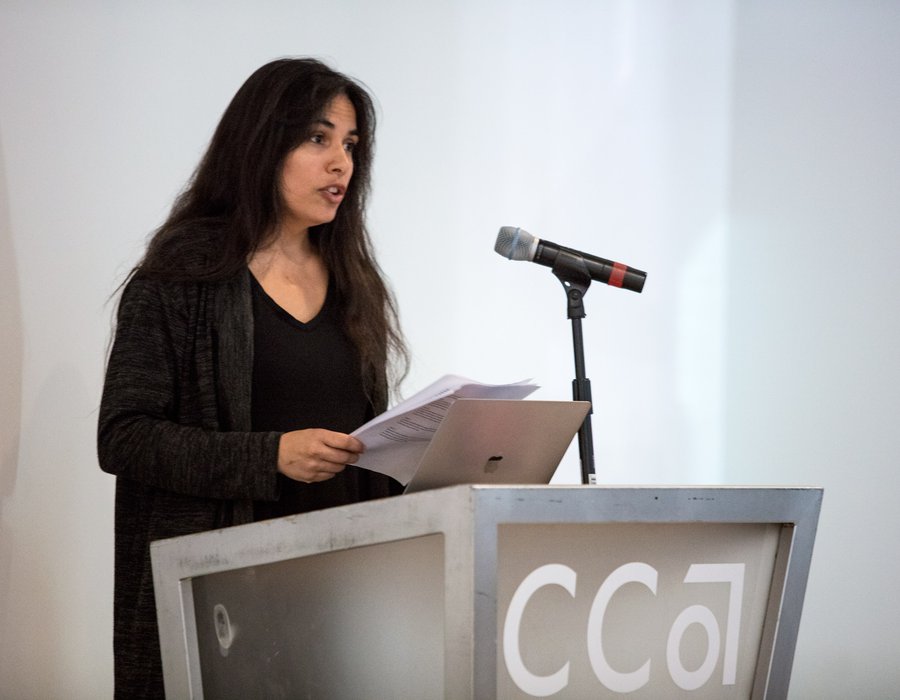 A student reads her thesis at a podium.