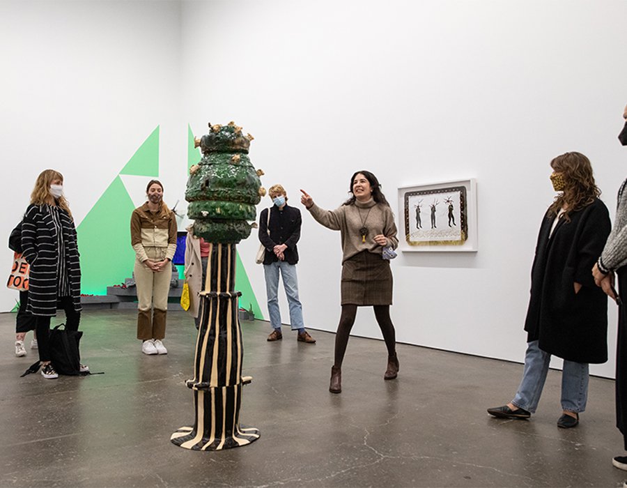 A group of Curatorial Practice students walk through a gallery show at Slash Art SF. One student points to a sculpture.