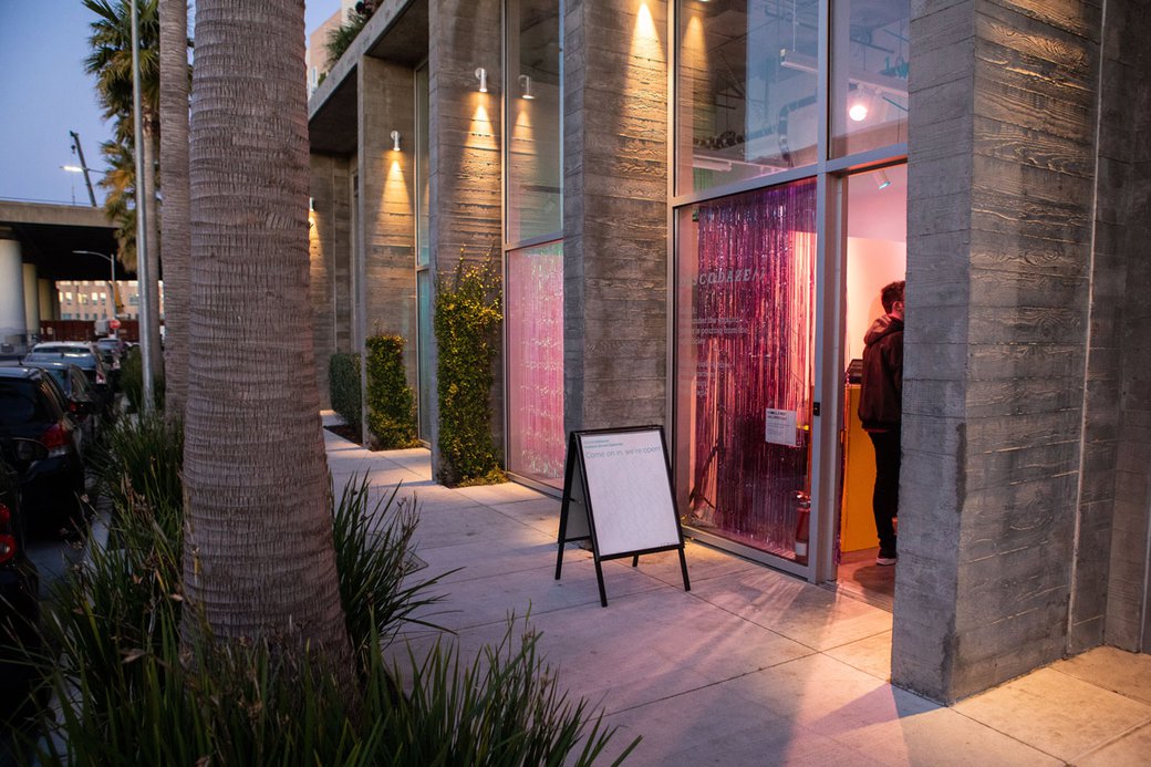 Pink light streams through the front door and window of PLAySPACE gallery