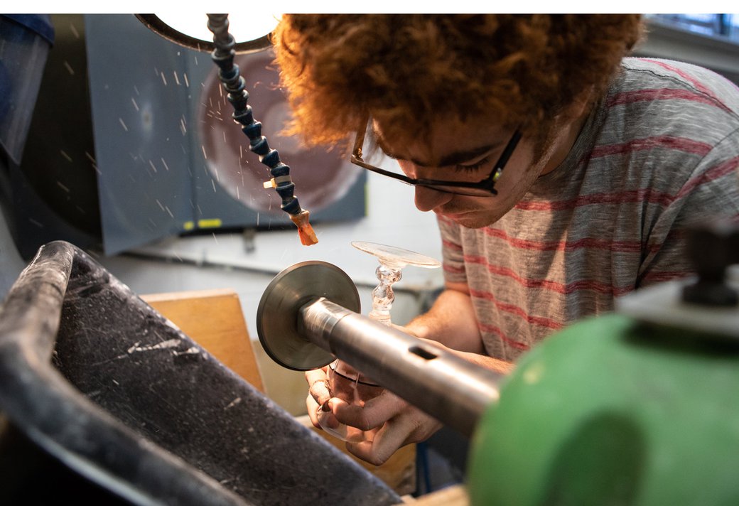 A young man grinds a glass chalice in the Cold Shop.
