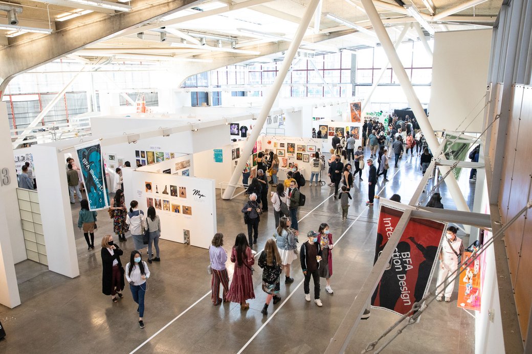 Crowds of people explore artwork in a lofty hall.