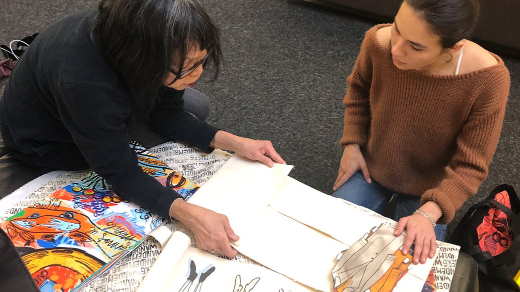 Fashion Design faculty May Liang and student Camila Wandemberg look over a portfolio of work.
