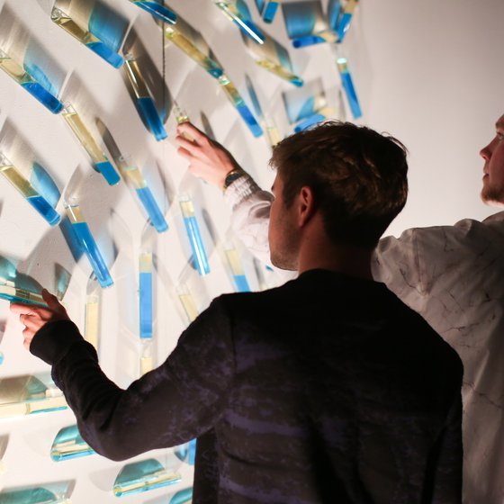 Two people engaging with fluid-filled vessels at an exhibition at Hubbell Street Galleries.