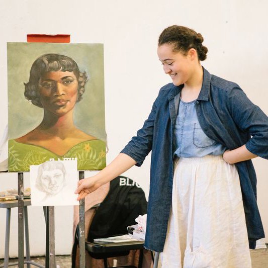 Painting and Drawing student holding up a sketch in front of their finished painting